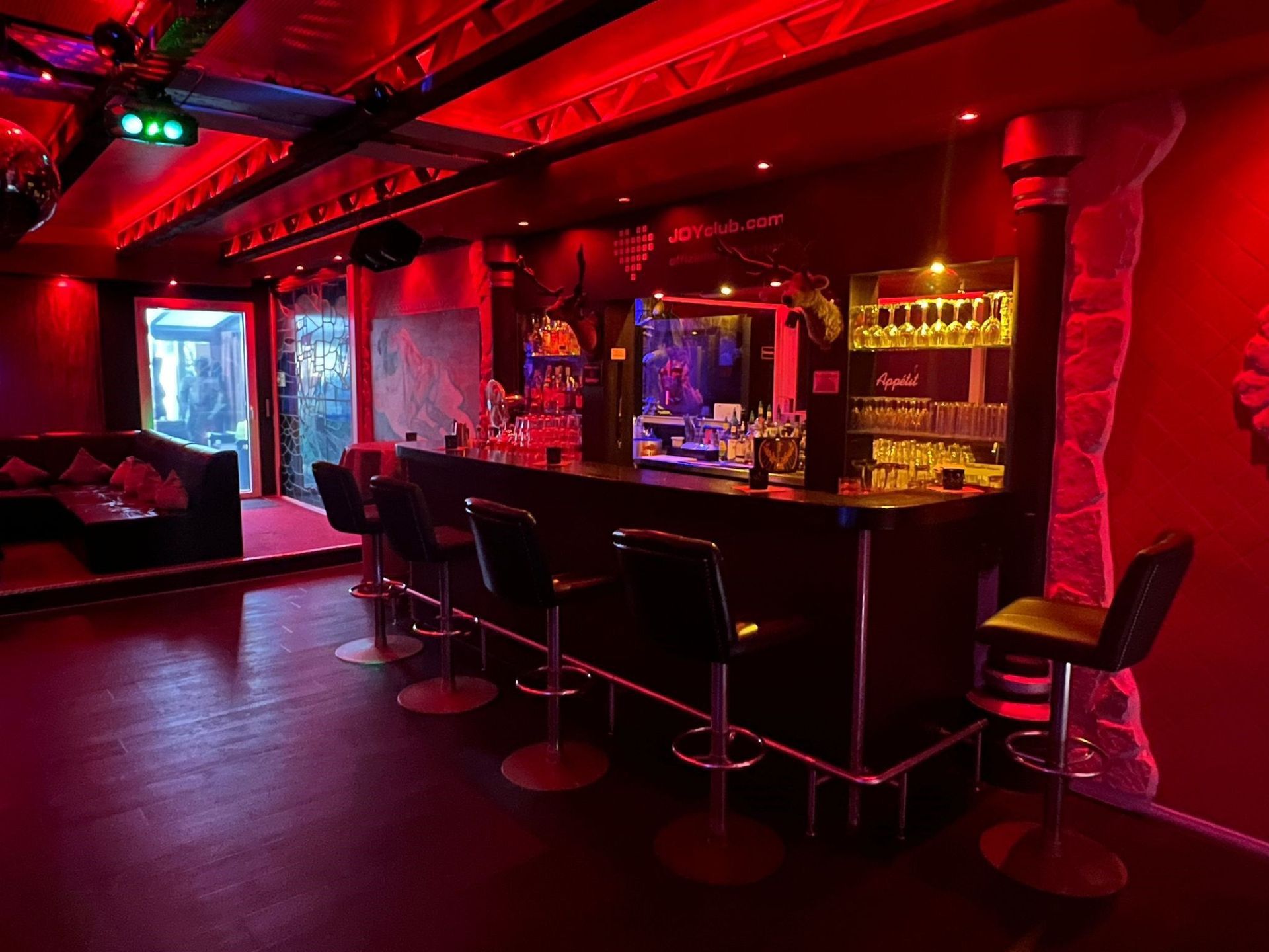 Es gibt eine Bar mit Barhockern, Getränke und eine Tür nach draußen.