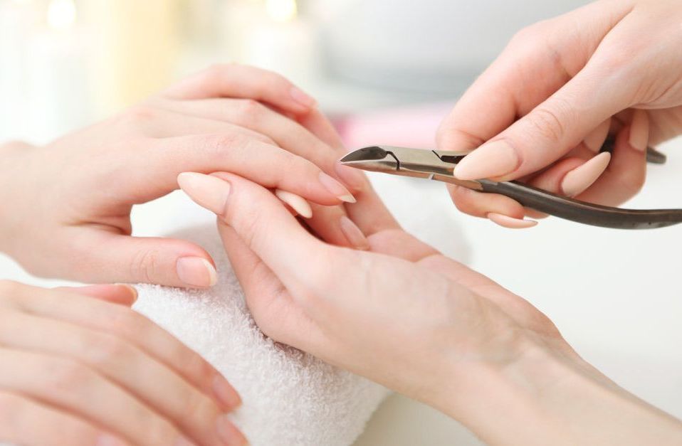 Una mujer se deja cortar las uñas por un técnico de uñas.