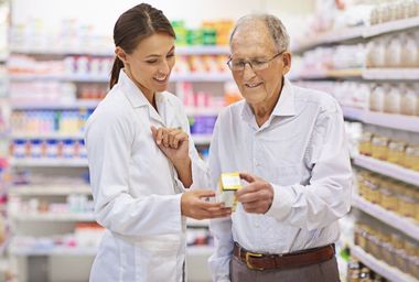 Una farmacéutica está hablando con un hombre mayor en una farmacia.