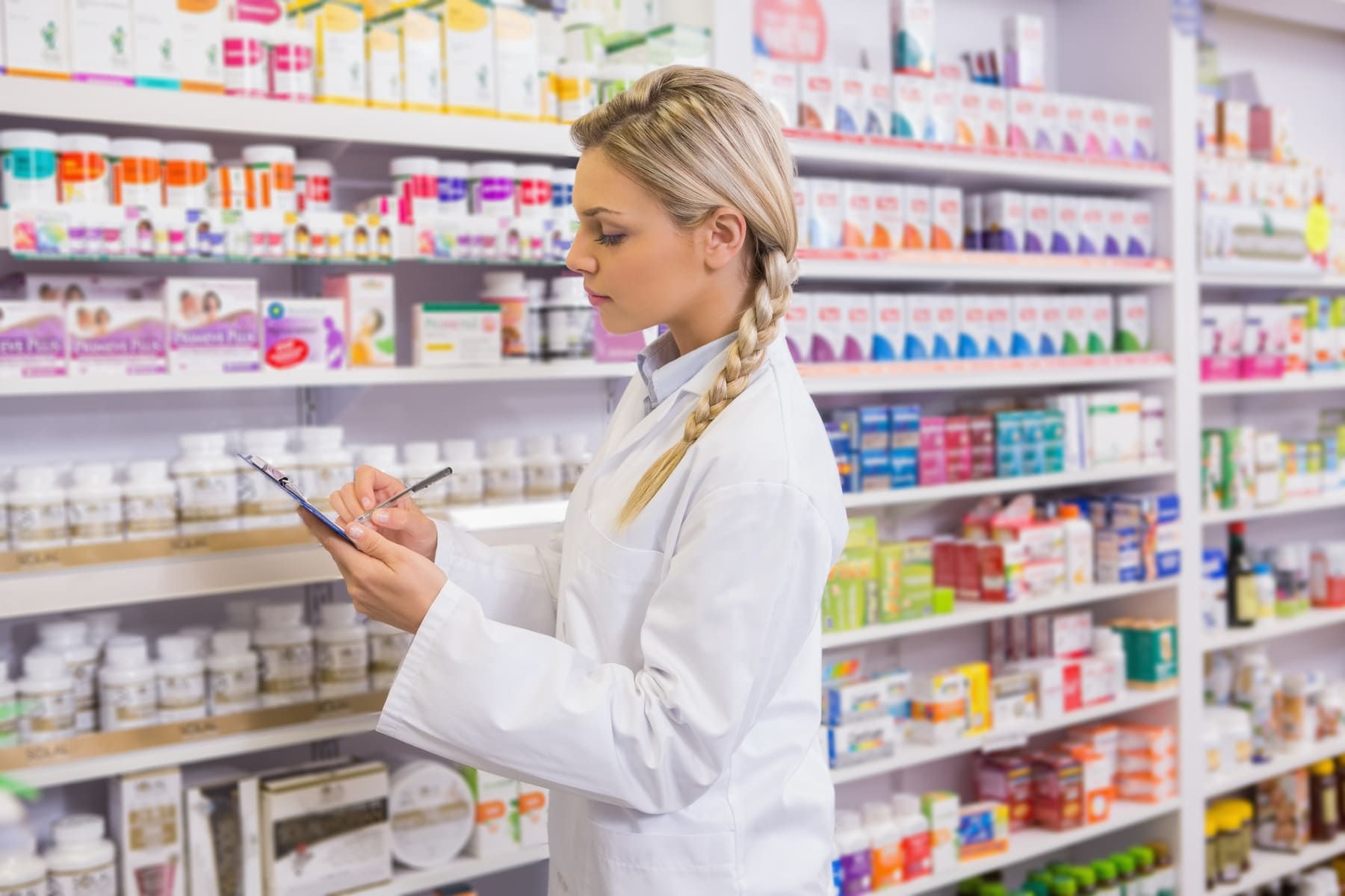 Una farmacéutica está mirando una tableta en una farmacia.
