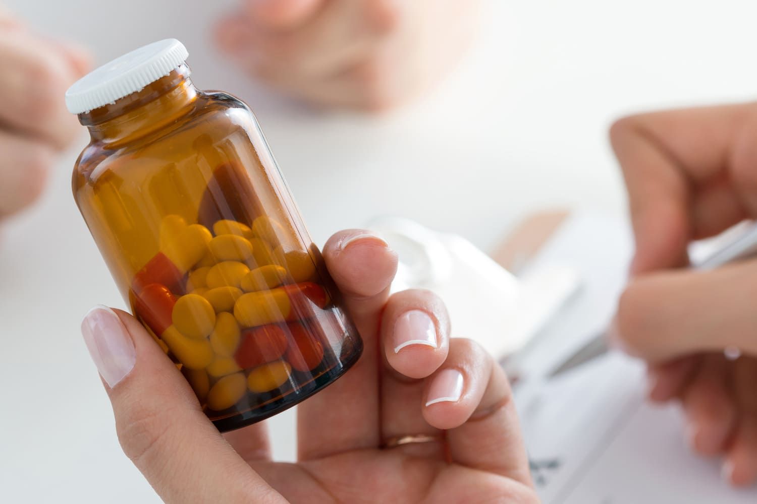 Una mujer sostiene un frasco de pastillas en su mano.