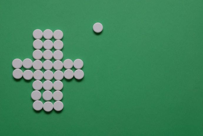 Una cruz hecha de pastillas blancas sobre un fondo verde.