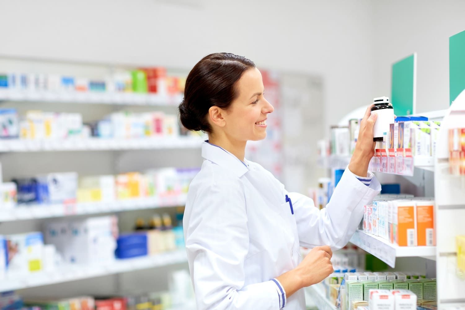 Una farmacéutica está mirando un frasco de medicamentos en una farmacia.