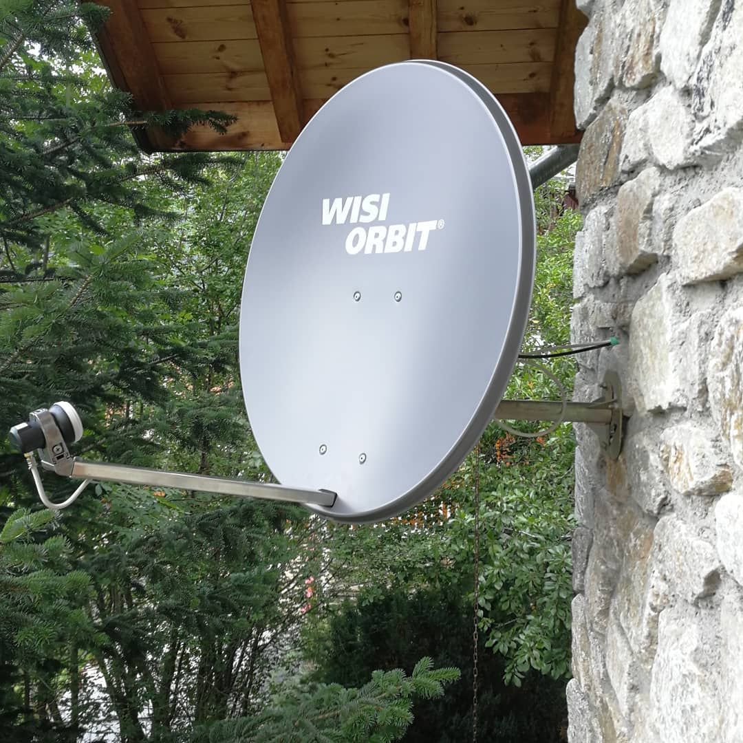 Une parabole TV sur le mur d'une façade de maison