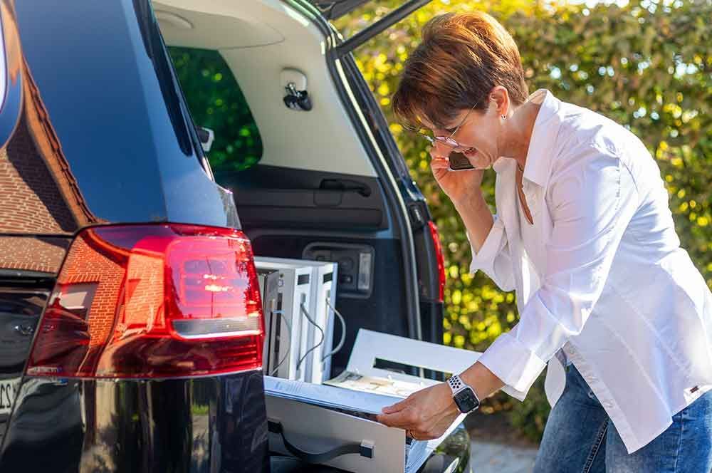 Eine Frau öffnet den Kofferraum eines Autos und telefoniert .