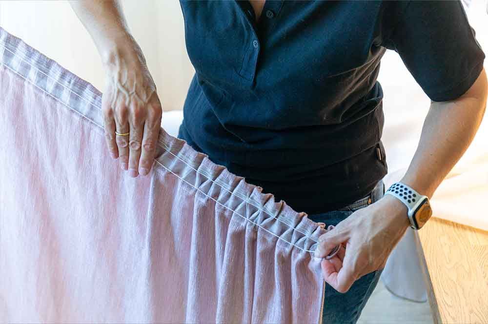 Eine Frau hält einen rosa Vorhang in ihren Händen .