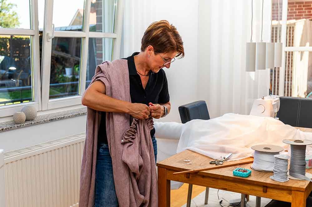 Eine Frau näht Vorhänge in einem Wohnzimmer .