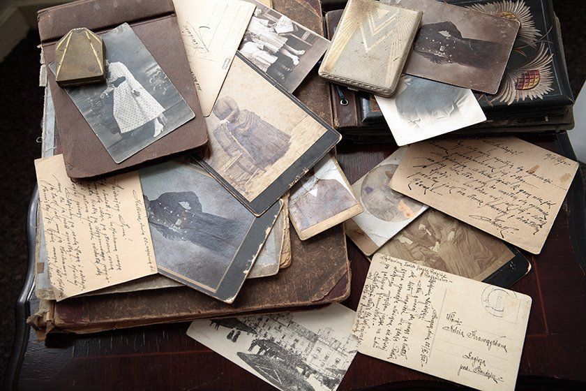 Multiples photos, cartes postales et livres en reliure cuir posés sur une table