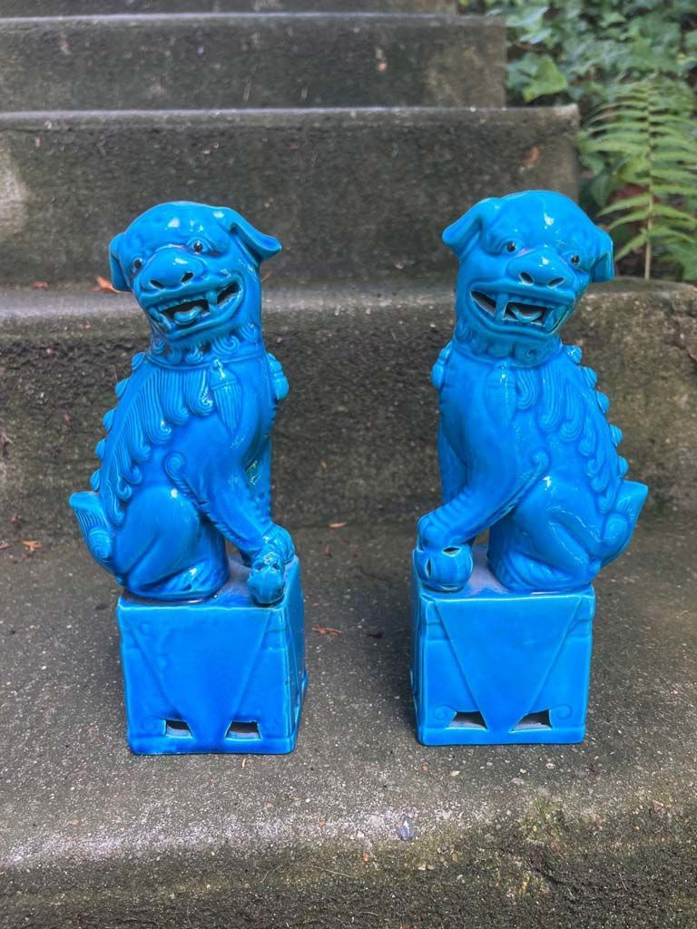 Deux statues de chiens Foo turquoise sur des marches.