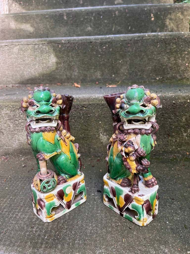 Deux chiens Foo en céramique verte et jaune sur des marches.