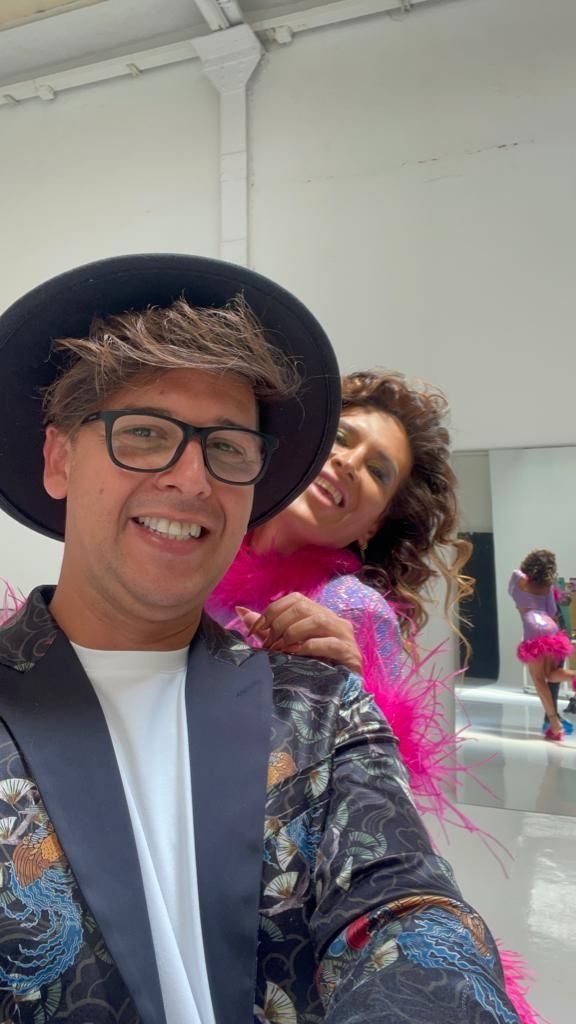 Un hombre que lleva un sombrero y gafas está de pie junto a una mujer que lleva una boa de plumas rosa.