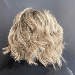 Una mujer con cabello rubio ondulado lleva una camisa negra.