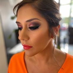 Un primer plano de una mujer vestida con maquillaje y una camisa naranja.