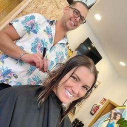 Un hombre está cortando el pelo a una mujer en un salón.