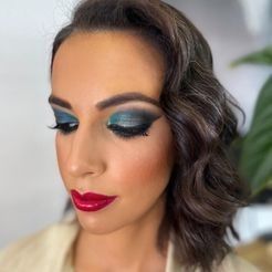 Una mujer lleva sombra de ojos azul y lápiz labial rojo.