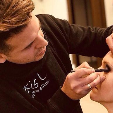 Un hombre está aplicando sombra de ojos en los ojos de una mujer.