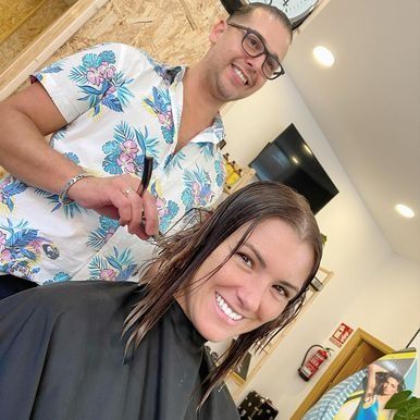 Un hombre está cortando el pelo a una mujer en un salón.