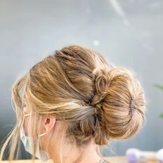 Una mujer lleva una mascarilla y tiene el pelo recogido en un moño.