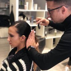 Un hombre está cortando el pelo a una mujer en un salón.