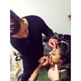 Un hombre está aplicando maquillaje en la cara de una mujer.