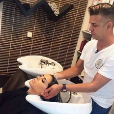 Un hombre está lavando el cabello de una mujer en un lavabo de un salón.