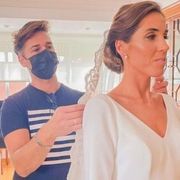 Un hombre que lleva una máscara está ayudando a una novia con su velo.