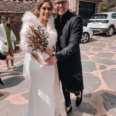 Una novia y un novio posan para una foto delante de un coche.
