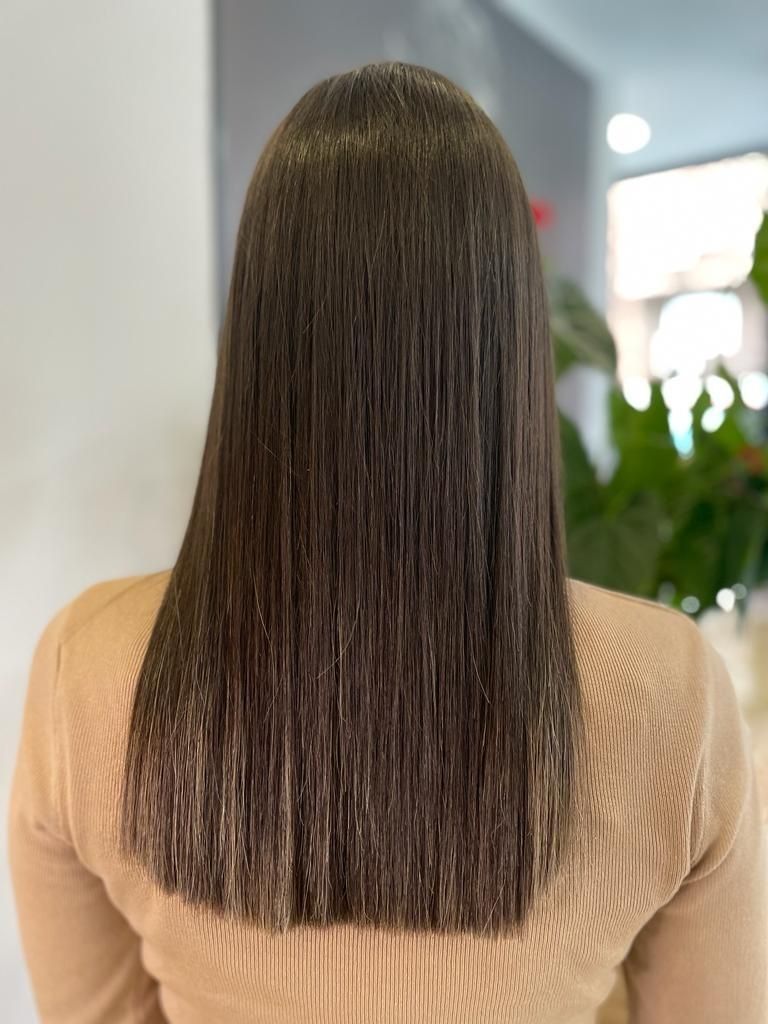 La parte posterior de la cabeza de una mujer con cabello largo y castaño.