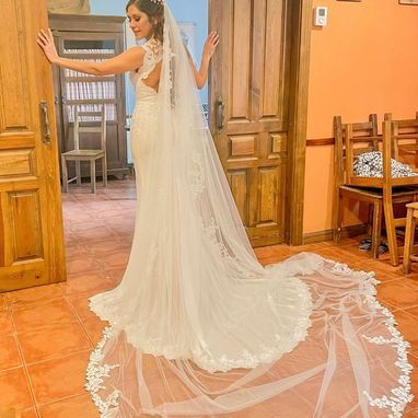 Una mujer con un vestido de novia y velo está de pie en una habitación.