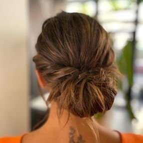 Una mujer lleva el pelo recogido en un moño y tiene un tatuaje en la espalda.