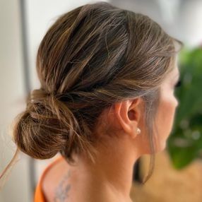 Una mujer lleva el pelo recogido en un moño.