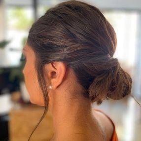 Una mujer lleva el pelo recogido en un moño.
