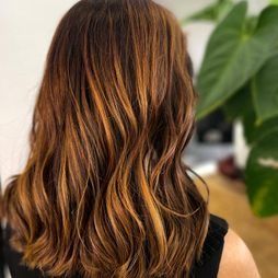 Una mujer con cabello largo y castaño lleva una camiseta sin mangas negra.