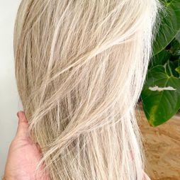 Una persona sostiene el cabello rubio de una mujer en su mano.