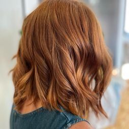 Una mujer con cabello rojo lleva una camisa azul.