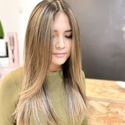 Una mujer con cabello largo está sentada en una mesa con los ojos cerrados.