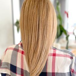 Una mujer con cabello largo y rubio lleva una camisa a cuadros.