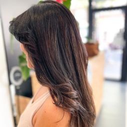 Una mujer con cabello largo y oscuro está parada en un salón.