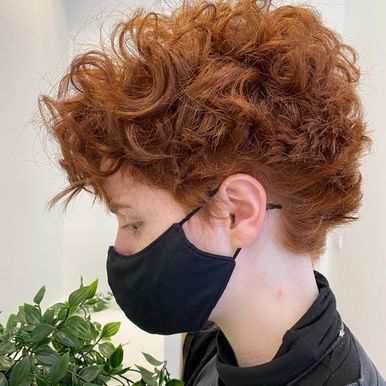 Una mujer con cabello rojo y rizado lleva una máscara negra.