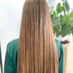 La espalda de una mujer con cabello largo que lleva una camisa verde.