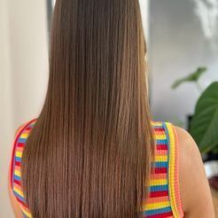 La espalda de una mujer con cabello largo que lleva una camiseta sin mangas colorida.