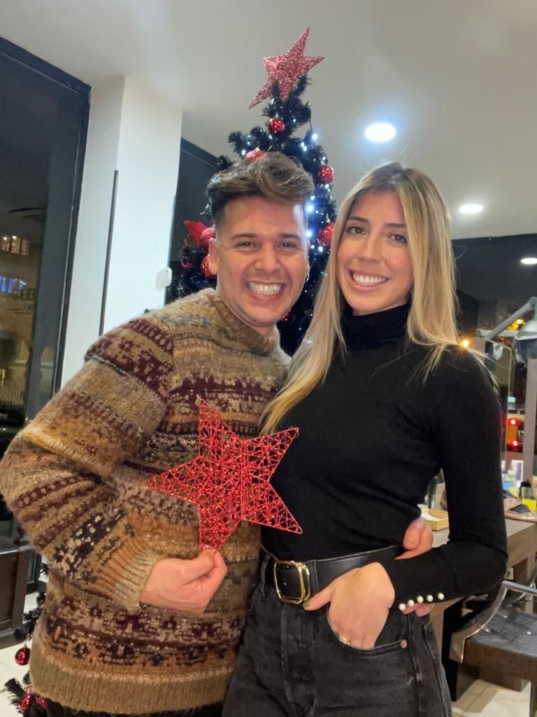 Un hombre y una mujer posan para una foto frente a un árbol de Navidad.