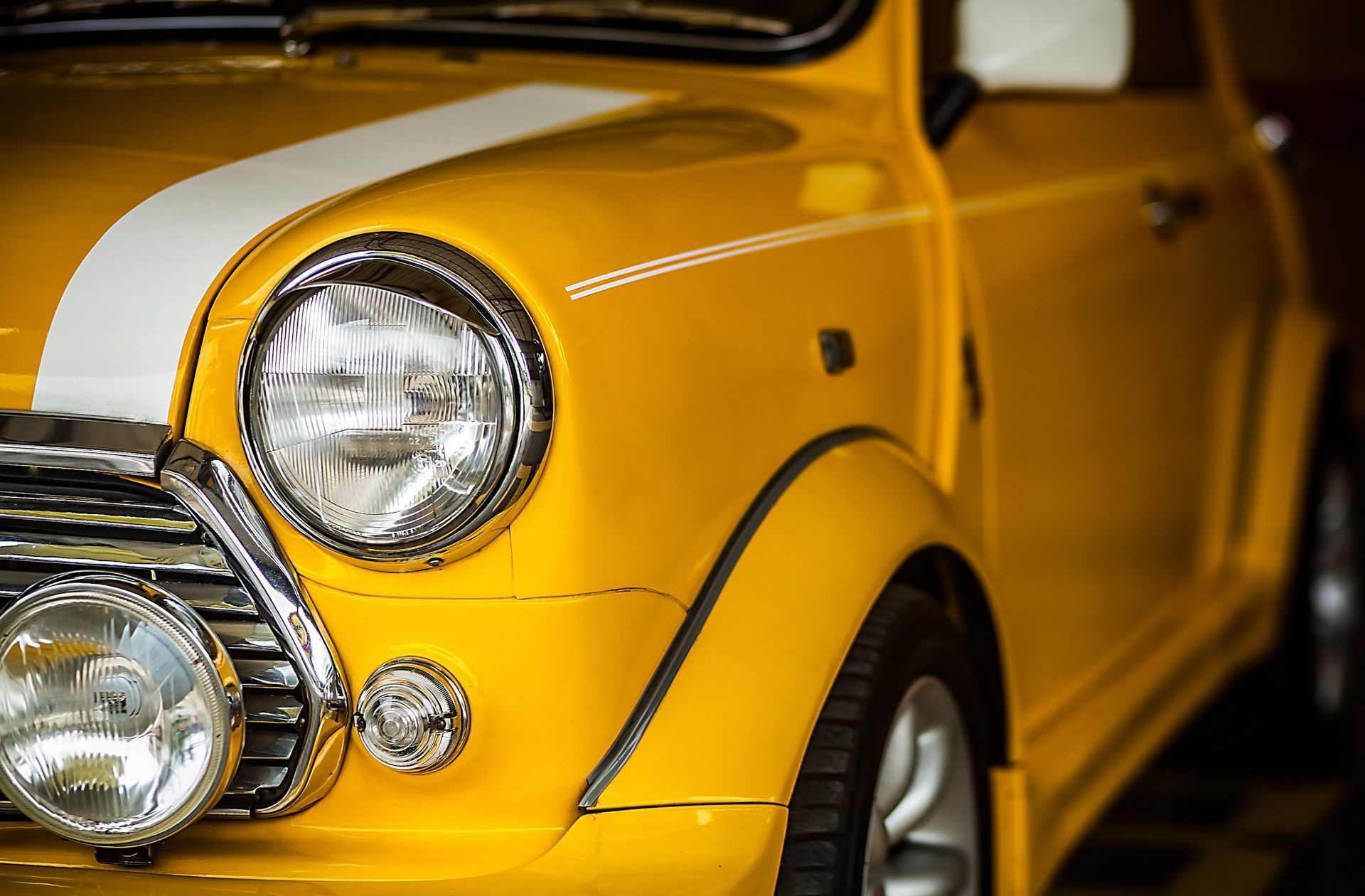 Un coche amarillo con una raya blanca en el lateral está aparcado en un garaje.