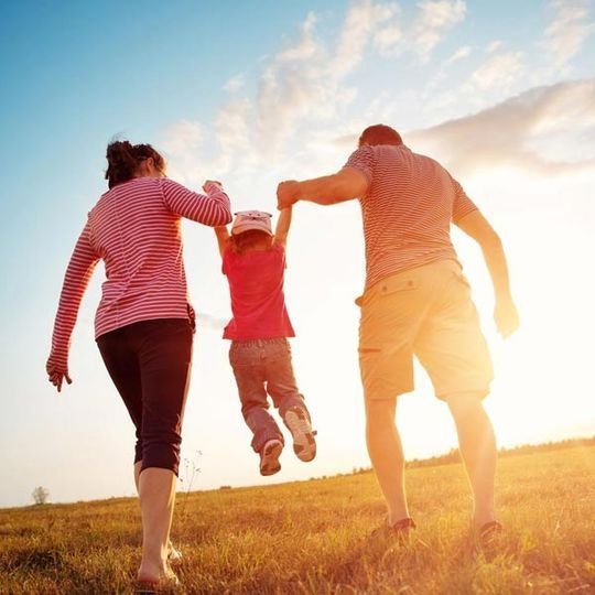 Una familia camina por un campo de hierba tomados de la mano