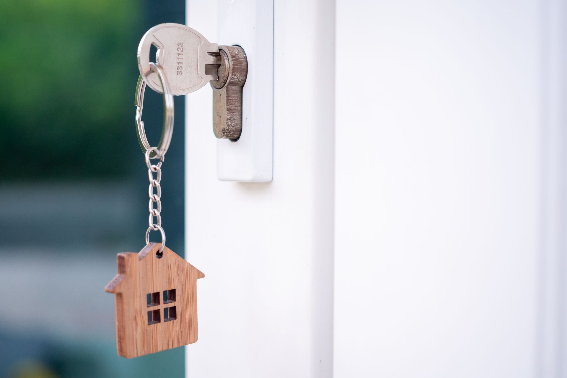 Clé insérée dans une serrure de porte avec porte-clés en forme de maison.