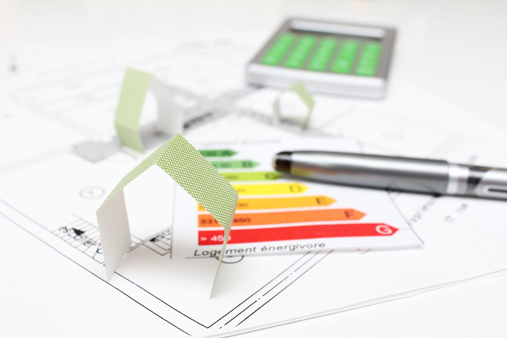 Tableau d'efficacité énergétique posé sur un bureau blanc, avec un stylo et une calculatrice.