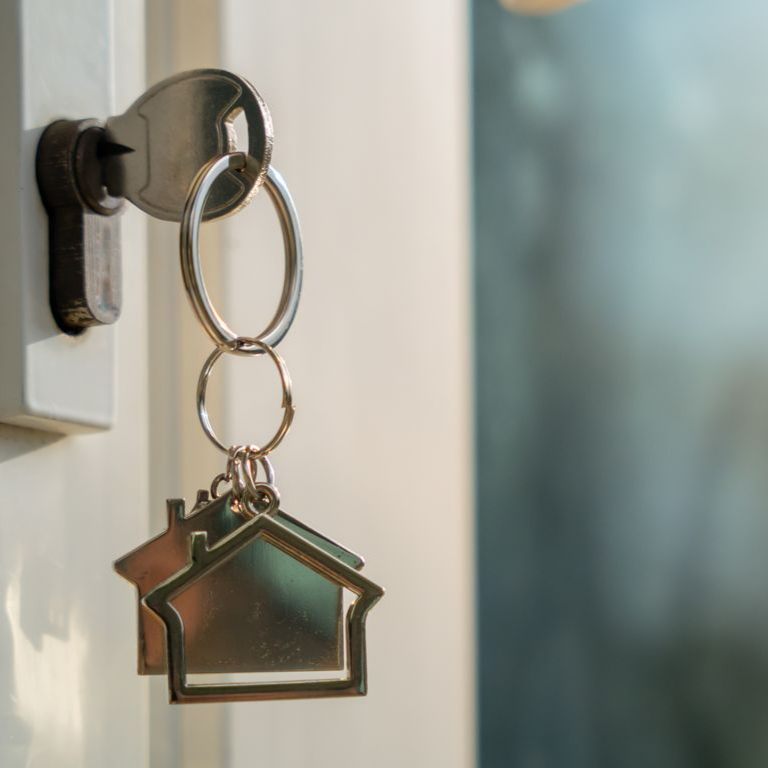 Porte-clés en forme de maison accroché à une clé insérée dans une serrure.