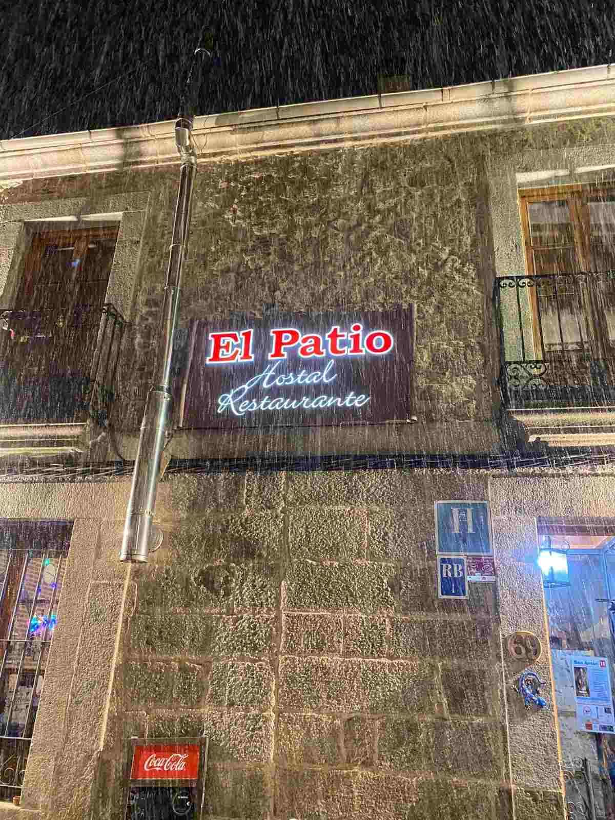 Foto nocturna del letrero del restaurante El Patio en un edificio de piedra, iluminado por luces brillantes.