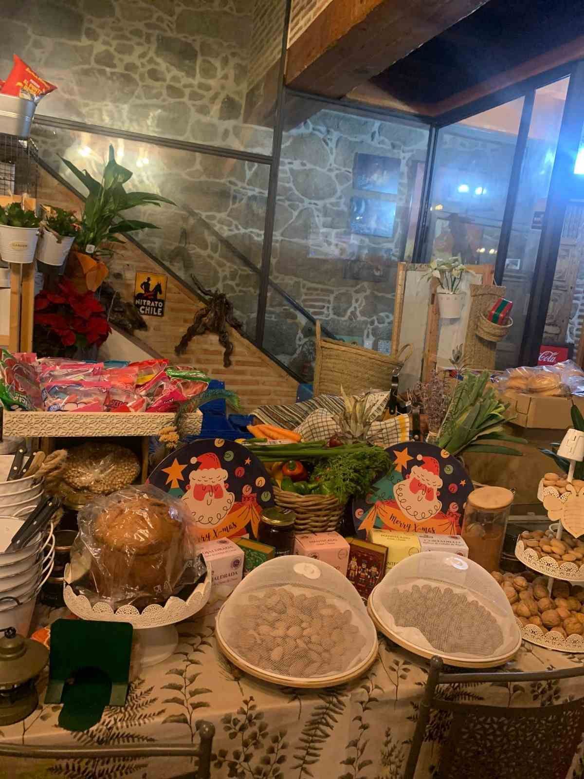 Mesa de buffet decorada con pasteles, bollería y arreglos florales en un acogedor comedor interior.