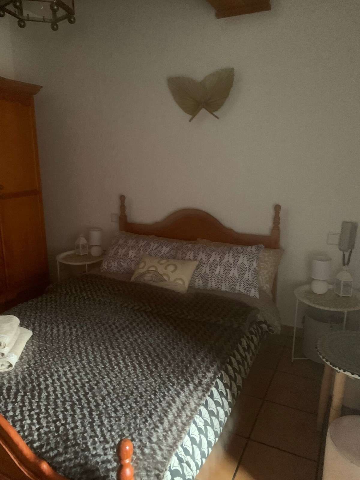 Dormitorio con cama de madera, colcha estampada y mesitas de noche.